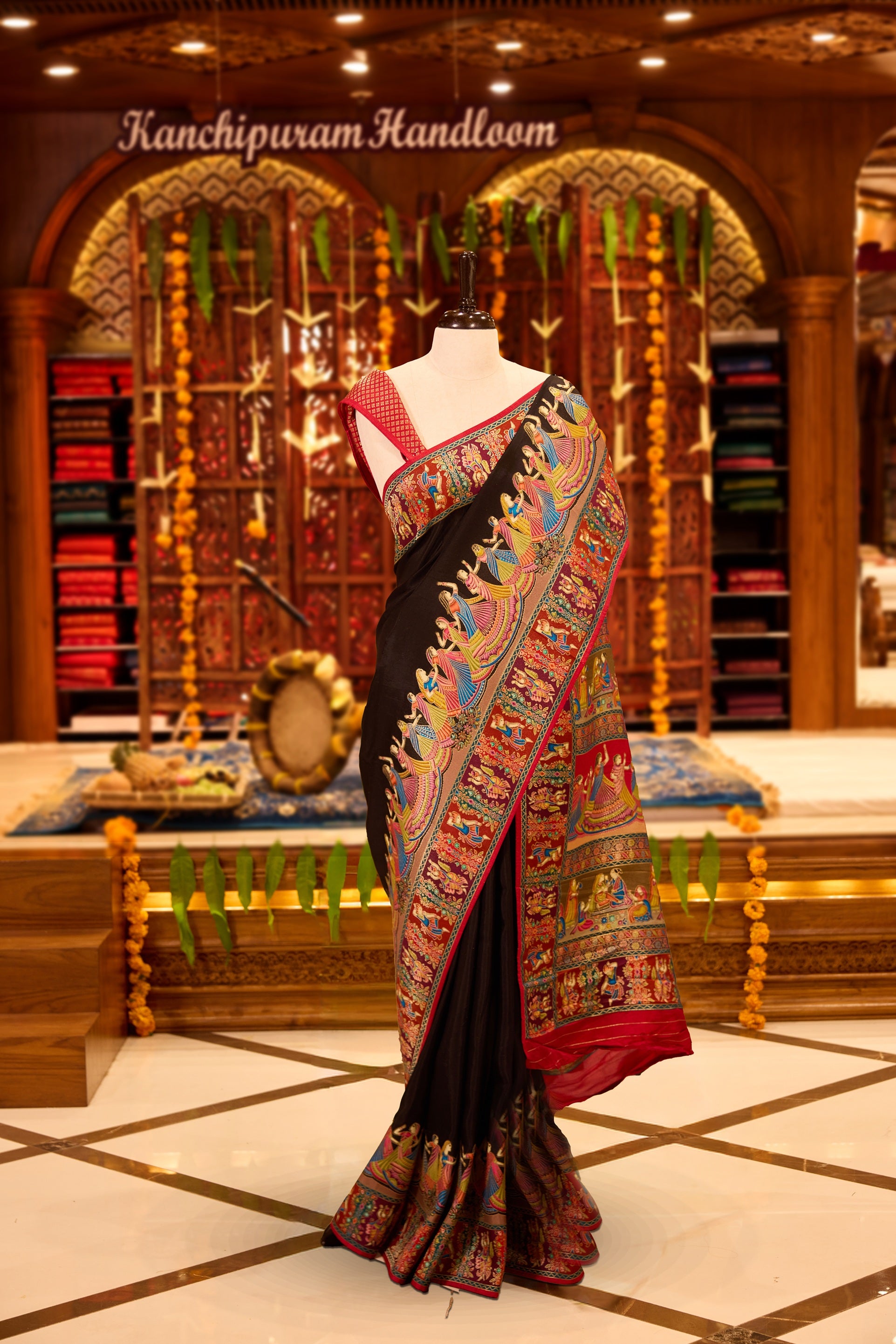 Black colour Pashmina silk saree exquisitely woven with vibrant mythological and architectural motifs across the body, bordered by elaborate narrative scenes and a grand artistic pallu, paired with a matching woven border blouse piece.