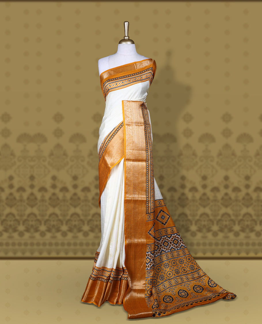 Beige Dolla silk saree featuring antique zari stripes across the body, adorned with a striking Ajrak and Traditional yellow colour border, ajrak printed pallu and paired with a perfectly matching blouse.