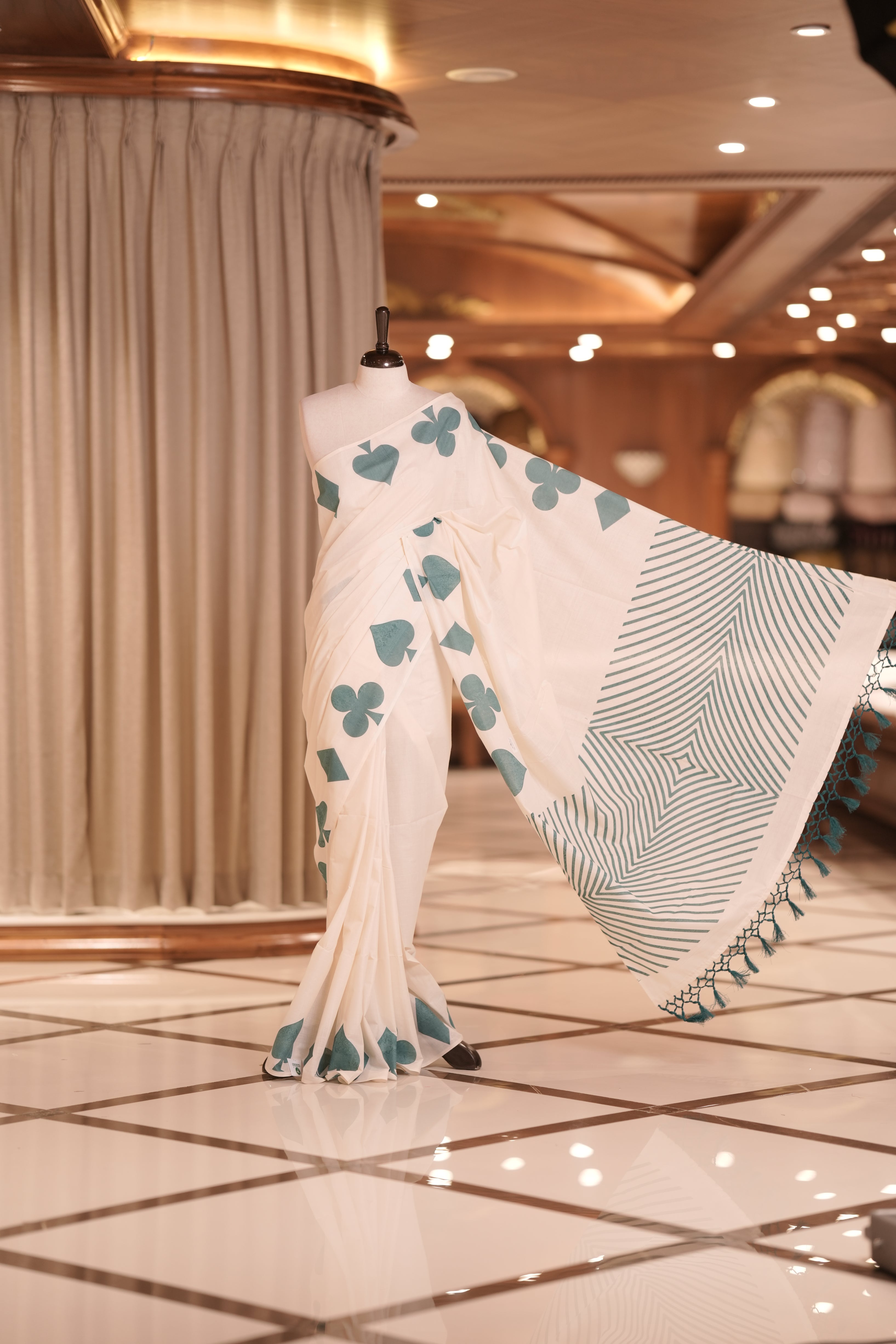 Off white colour kerala cotton saree adorned with peacock green card suit motifs , The pallu features striking zigzag patterns with tassel detailing, creating a perfect fusion of tradition and modern sophistication.