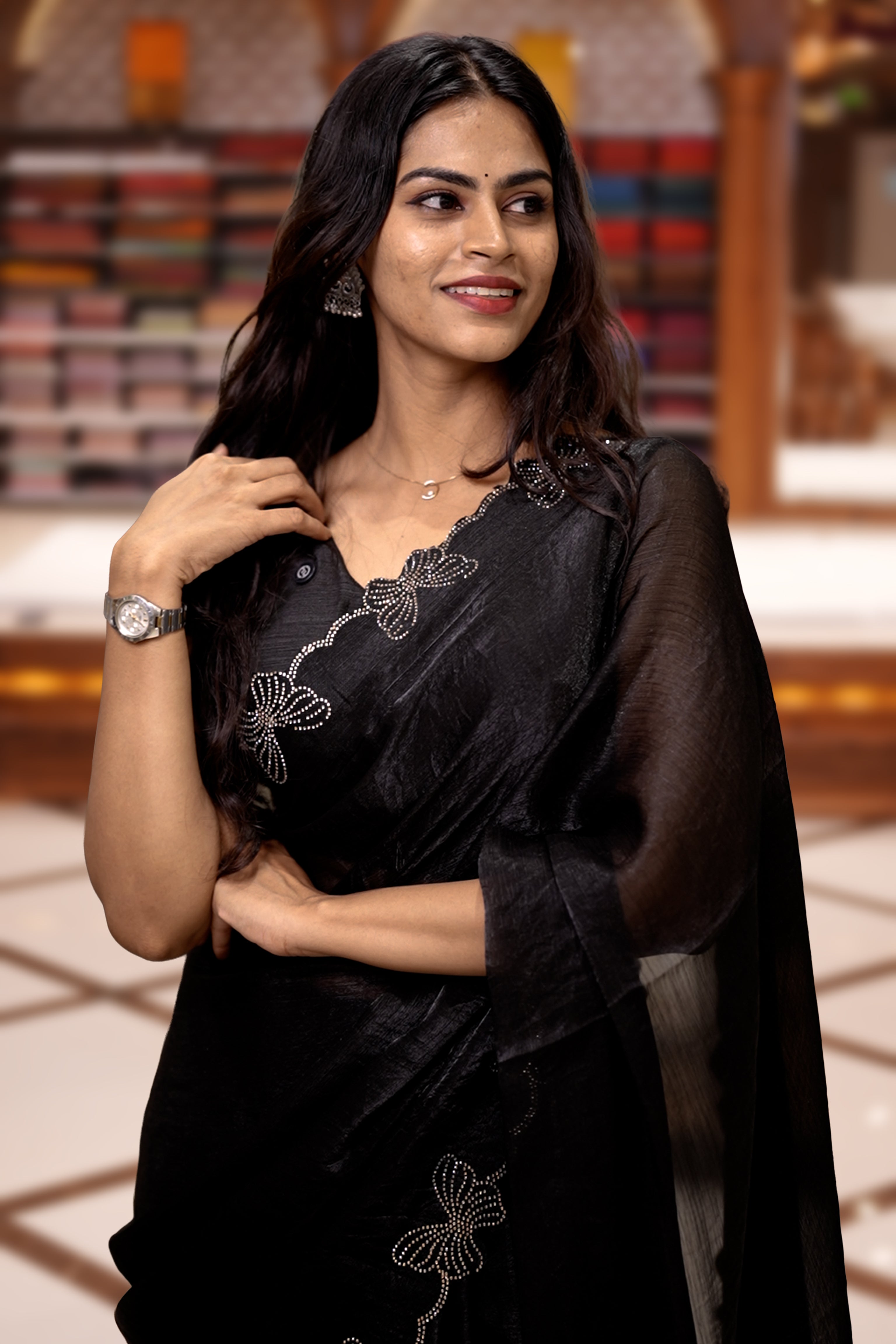 Black colour chiffon saree adorned with Swarovski stone butterfly designs along the side border, adding a touch of sparkle, Paired with a matching blouse piece featuring the same intricate stone work.