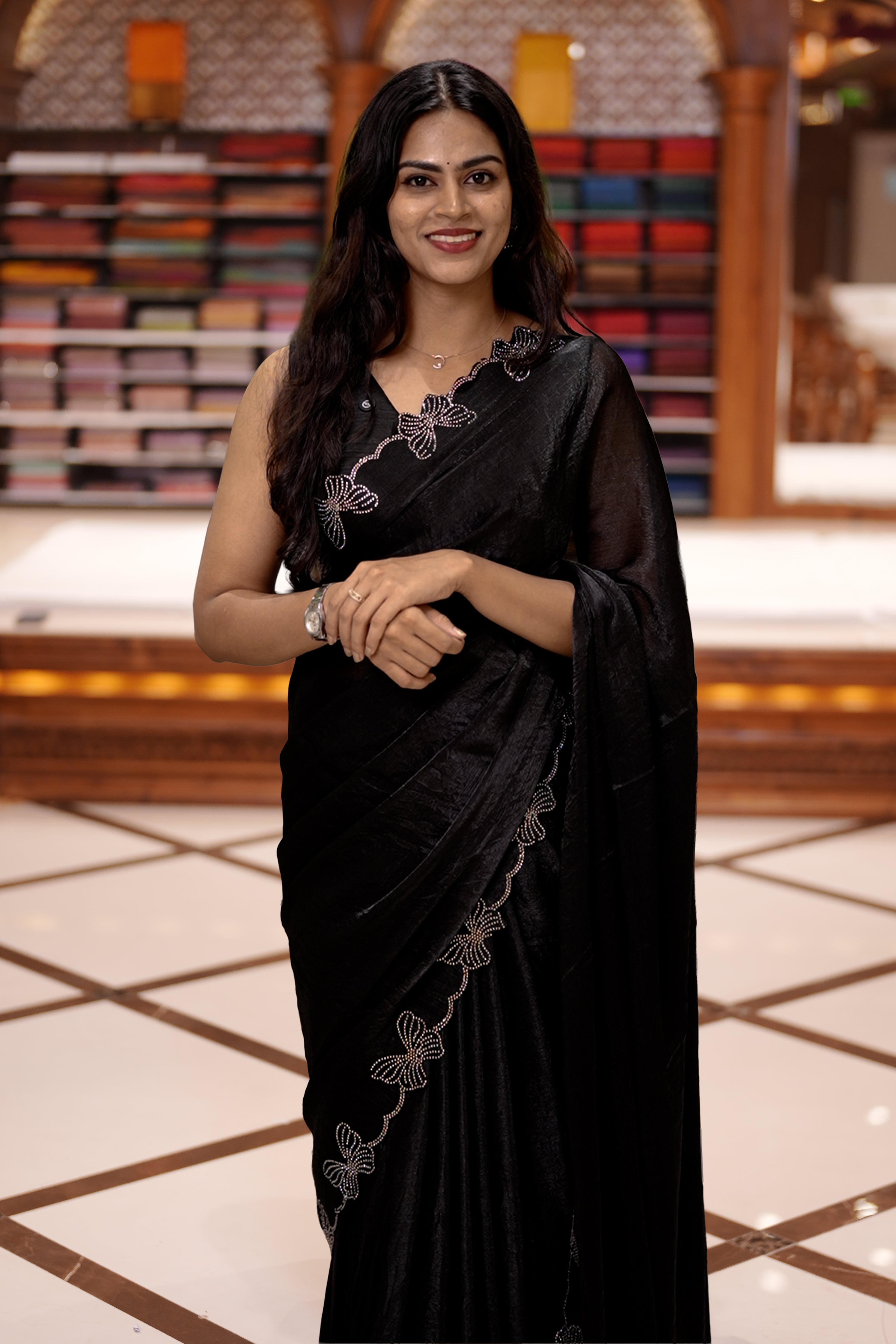 Black colour chiffon saree adorned with Swarovski stone butterfly designs along the side border, adding a touch of sparkle, Paired with a matching blouse piece featuring the same intricate stone work.