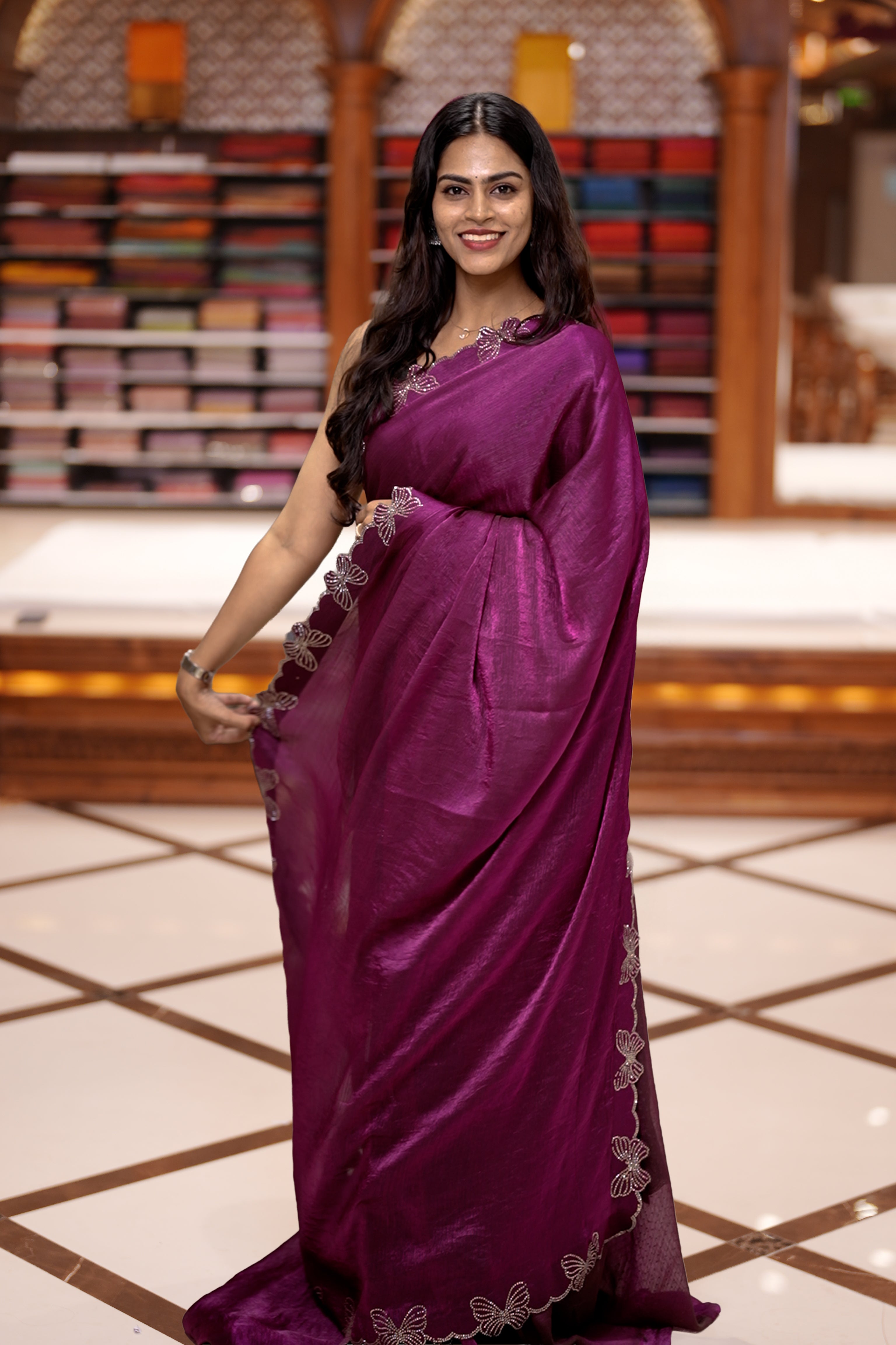 Purple colour chiffon saree adorned with Swarovski stone butterfly designs along the side border, adding a touch of sparkle, Paired with a matching blouse piece featuring the same intricate stone work.
