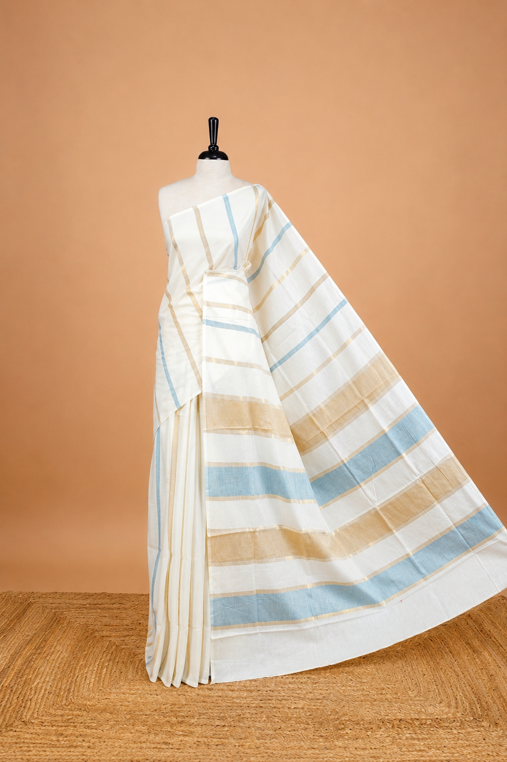 Cream Colour Cotton Kerala Saree Featuring Blue & Gold Zari Strips On The Body & Pallu, Paired With A Matching Blouse Piece.