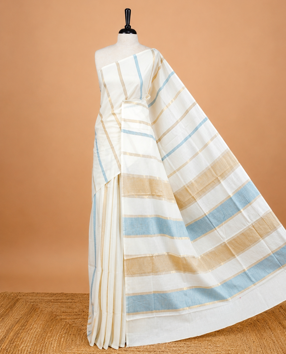 Cream Colour Cotton Kerala Saree Featuring Light Blue & Gold Zari Strips On The Body & Pallu, Paired With A Matching Blouse Piece.