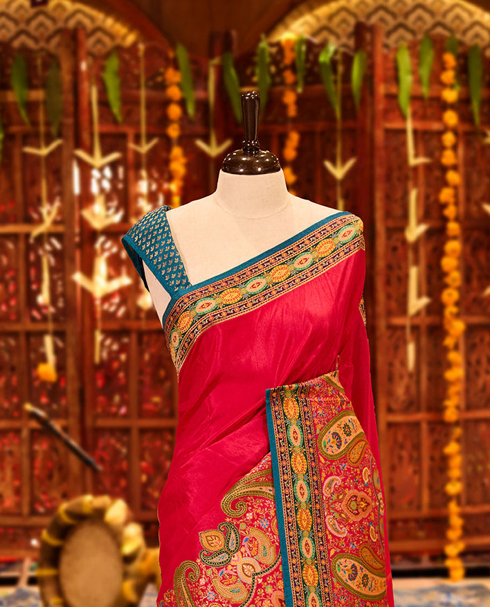 Magenta colour Pashmina silk saree beautifully woven with intricate paisley and floral motifs in vibrant multicolour weaves, framed by teal and gold ornamental borders and an elaborate artistic pallu, paired with a coordinated woven blouse piece.