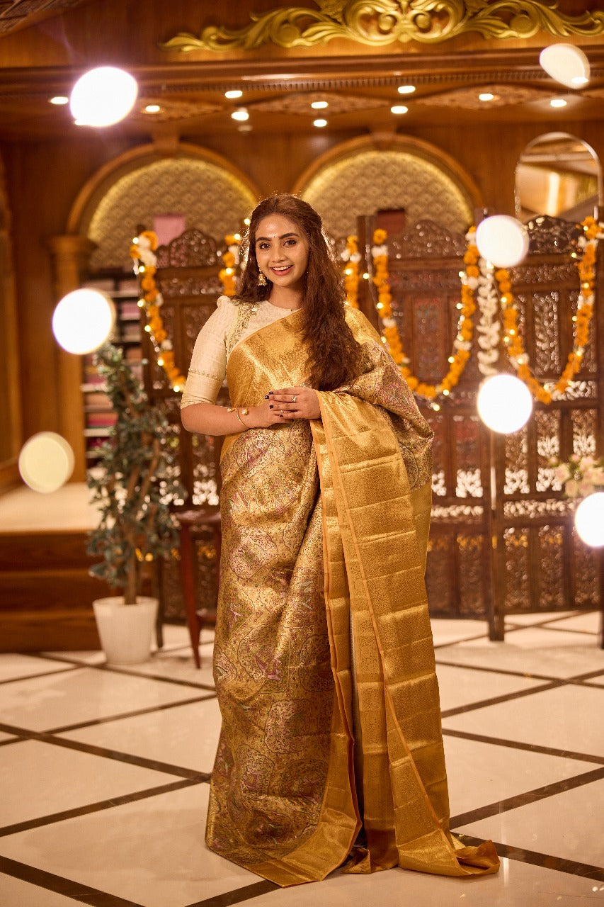 Gold colour Kancheepuram handloom tissue saree with Meena floral design, gold zari border and pallu, paired with matching blouse piece.