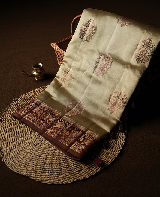 Cream Beige Colour Banaras Soft Silk Saree with Gold Zari Mandala Oval Buttas, Intricate Multi-Layered Floral and Foliate Pallu Border, Grand Pallu with Ornate Peacock Motifs in Burgundy and Gold Tones, and Matching Rust Orange Blouse.