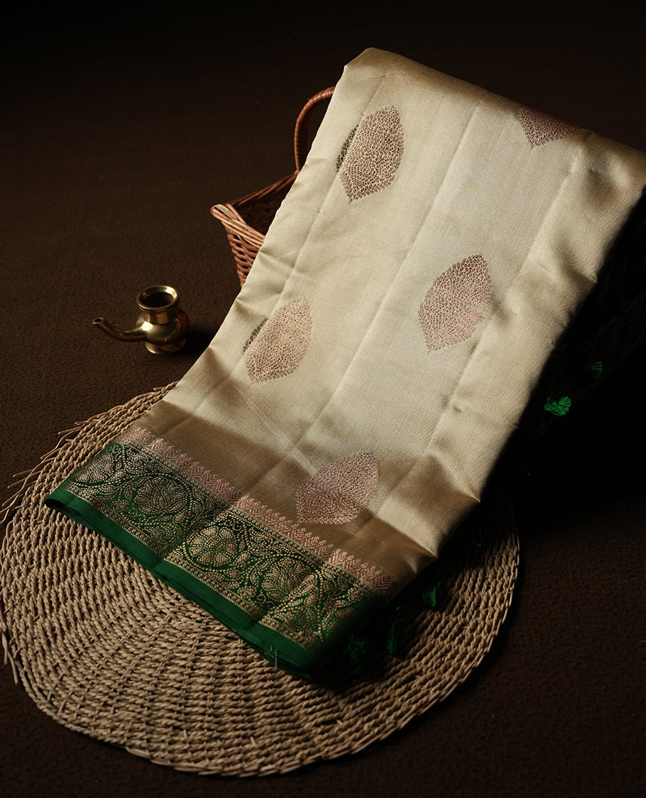 Golden Yellow Colour Banaras Soft Silk Saree with Gold Zari Textured Oval Buttas, Simple Decorative Pallu Border, Pallu with Ornate Floral and Foliate Motifs in Green and Gold Tones, and Matching Forest Green Blouse.