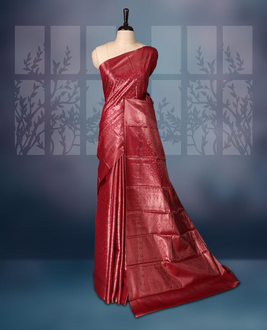 Maroon colour semi silk brocade saree featuring intricate self design brocade patterns across the body, complemented by a rich self colour woven border and pallu, paired with a matching blouse.