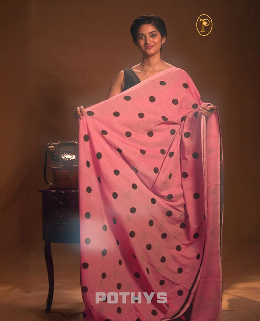 Light red colour Mul cotton saree featuring polka dot prints across the body, accented with a subtle small border, without a blouse piece.