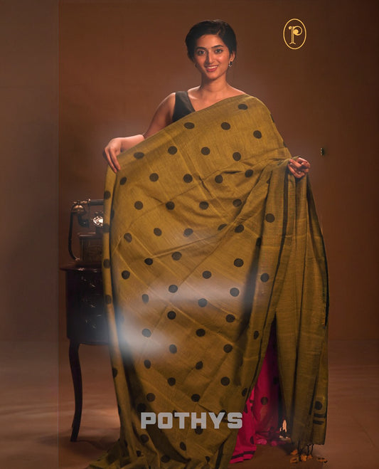 Olive green colour Mul cotton saree featuring polka dot prints across the body, accented with a subtle small border, without a blouse piece.