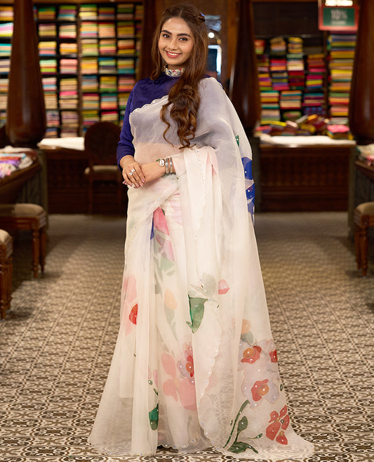 White colour pure organza silk saree featuring digitally printed fancy floral designs, adorned with delicate small mirror work, and finished with an elegant scalloped border, paired with a self colour crepe printed blouse
