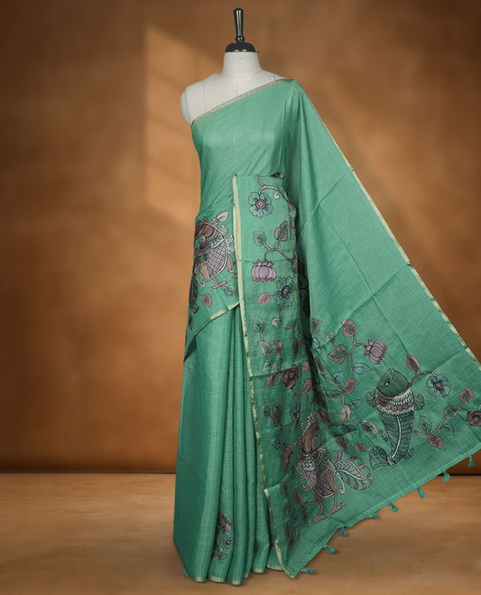 Mint green semi linen saree featuring hand painted floral and bird motifs across the pallu and border finished with subtle tassel detailing and paired with a matching floral print blouse