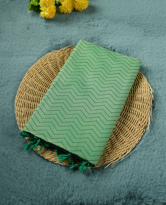 Pista Green colour poly cotton saree with black zigzag line pattern on the body, paired with a matching pallu featuring black chevron lines and panelled floral‑paisley design, and a coordinated all‑over floral paisley patch‑style printed blouse piece.