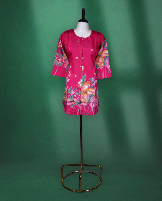 Fuchsia pink colour short kurti featuring a round neck and three quarter sleeves, adorned with vivid orange floral prints and minimal front buttons for a vibrant, breezy look.