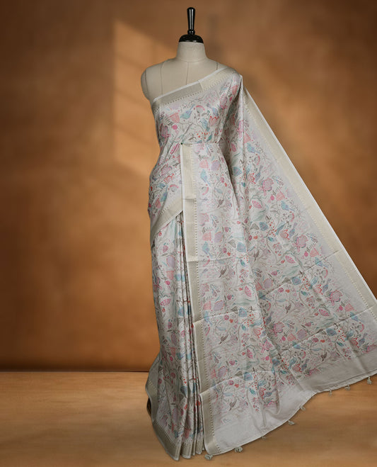Cream colour semi tussar silk saree featuring all over floral and leaf motifs on the body with a subtle self border and tasselled pallu, paired with a matching blouse.