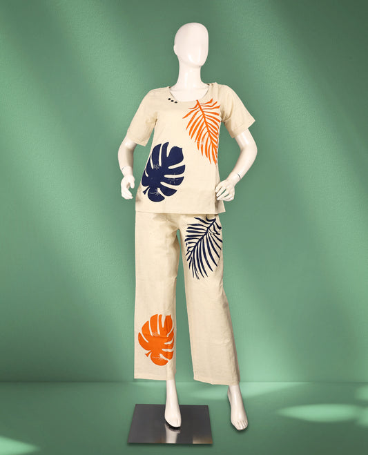 Beige colour cotton nightwear featuring bold navy blue and orange tropical leaf prints, a round neck top with short sleeves, and relaxed-fit ankle-length pants for a vibrant and breezy casual look.