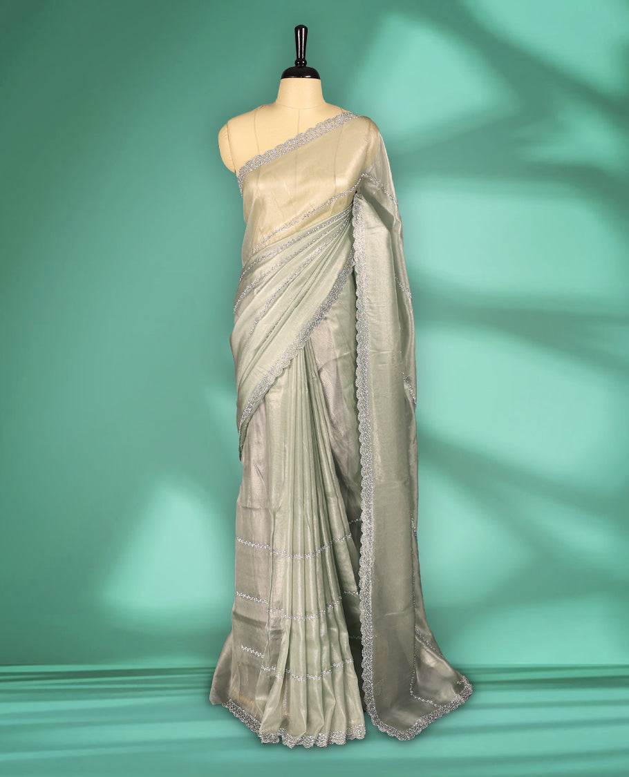 Light Pastel Green colour net shimmer fancy saree adorned with subtle horizontal White stone patterns on the body, paired with a delicate stone worked border, with matching blouse