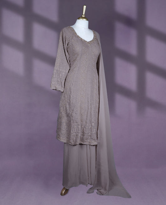 Taupe colour salwar set featuring a V neckline with subtle embellishments, three-quarter sleeves, intricate all-over embroidery, a matching chiffon dupatta, and a coordinated bottom