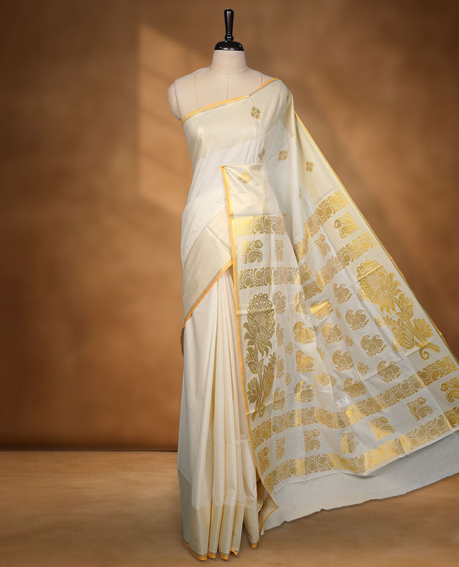 off-white cotton Kerala saree adorned with rich gold zari motifs across the pallu, finished with a classic kasavu border and subtle buttas on the body, paired with a matching blouse