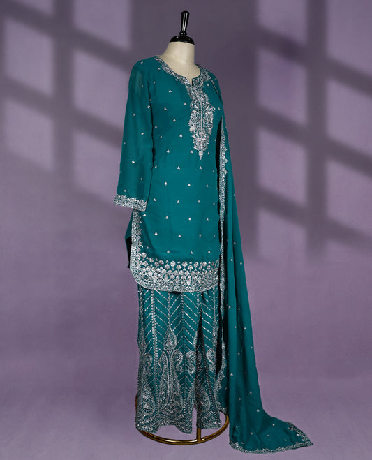 Teal green colour sharara set featuring a notched round neckline, three quarter sleeves, exquisite silver embroidery, flared embroidered bottoms, and a matching embellished dupatta