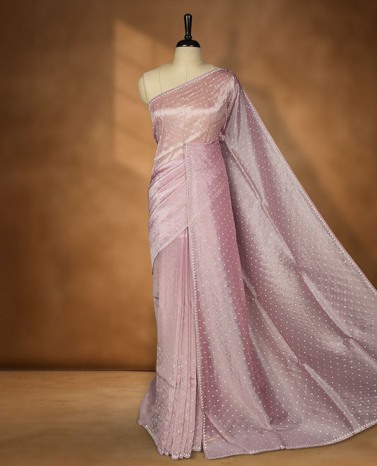 Pink colour net shimmer fancy saree adorned with scattered white stone buttas all over the body, paired with a delicate stone worked border and matching blouse.