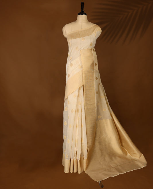 Light gold colour Organza Kerala saree featuring Gold zari Motifs on the body, Gold Kasavu border, Comes paired with a coordinated matching blouse.