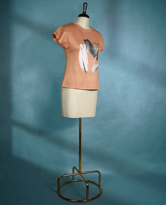 Peach toned T shirt with cap sleeves, featuring bold abstract paint style strokes in pastel and metallic hues for an artistic and modern flair.