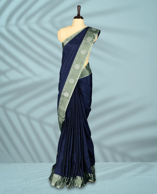 Navy blue Colour semi silk saree features Zari worked body enhanced by a pastel green zari border adorned with Silver circular motifs, and comes with a matching blouse.
