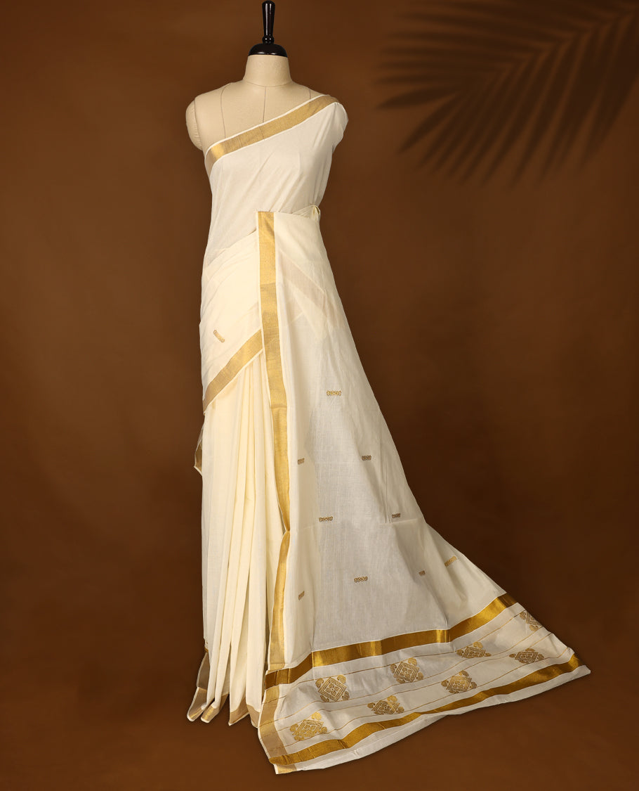 Traditional off white colour cotton Kerala saree with golden zari border and temple motif pallu, Accented with small golden buttas and paired with a matching blouse, Ideal for festive and cultural events.