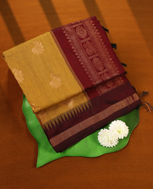Mustard colour Kalyani cotton saree adorned with zari woven buttas across the body, paired with a rich Maroon colour traditional zari border and pallu, with matching blouse.