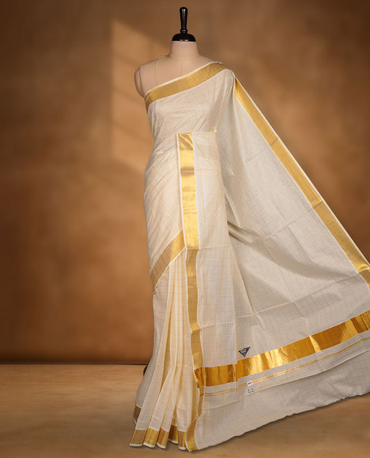 Off-white colour cotton Kerala saree featuring a classic gold kasavu border, highlighted by subtle woven check patterns across the body and pallu, and paired with a matching blouse.