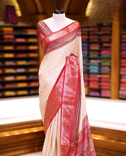 Beige Dolla silk saree featuring antique zari stripes across the body, adorned with a striking Ajrak and Traditional red colour border, ajrak printed pallu and paired with a perfectly matching blouse.