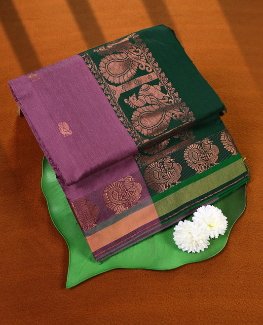 Lavender pink and Dark Green Kalyani cotton saree featuring intricately woven golden peacock and paisley motifs across the border and pallu, highlighted with a zari finish, and paired with a matching blouse.
