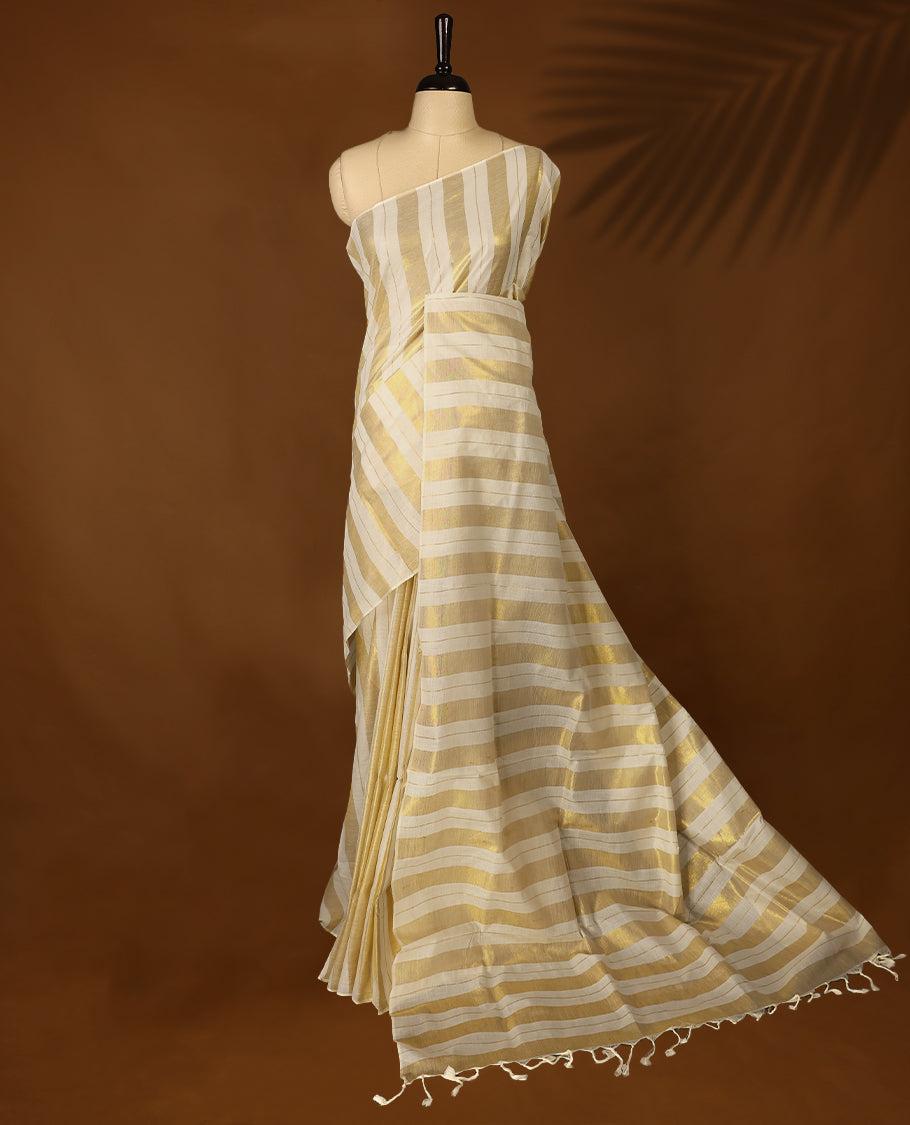White & gold colour striped Kerala saree featuring  a sheer, smooth body, without border, Comes paired with a coordinated matching blouse.
