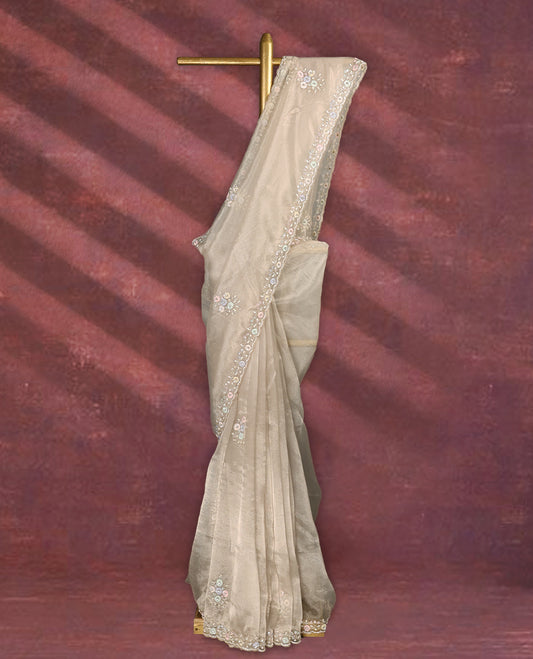 Deep beige colour pure organza saree featuring all over floral sequin work, adorned with a matching intricately worked floral border, complemented by a richly embellished pallu and paired with a heavily worked matching blouse.
