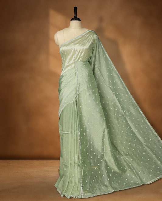 Pastel Mint colour net shimmer fancy saree adorned with white stone buttas all over the body, paired with a delicate stone worked border, with matching blouse