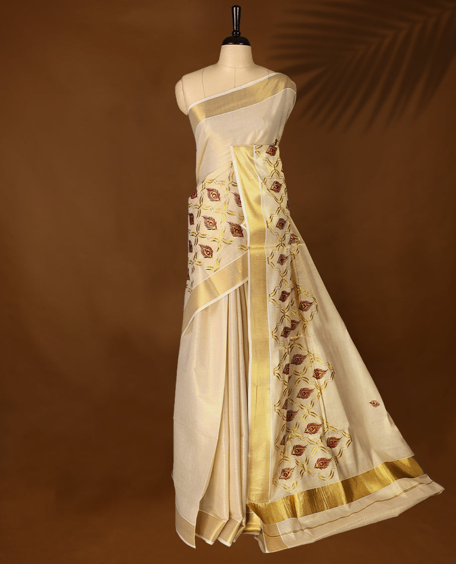 Elegant Light Gold colour Tissue Kerala saree featuring peacock feather embroidery worked body and traditional golden zari kasavu border offering a classic and graceful look, paired with a matching blouse.