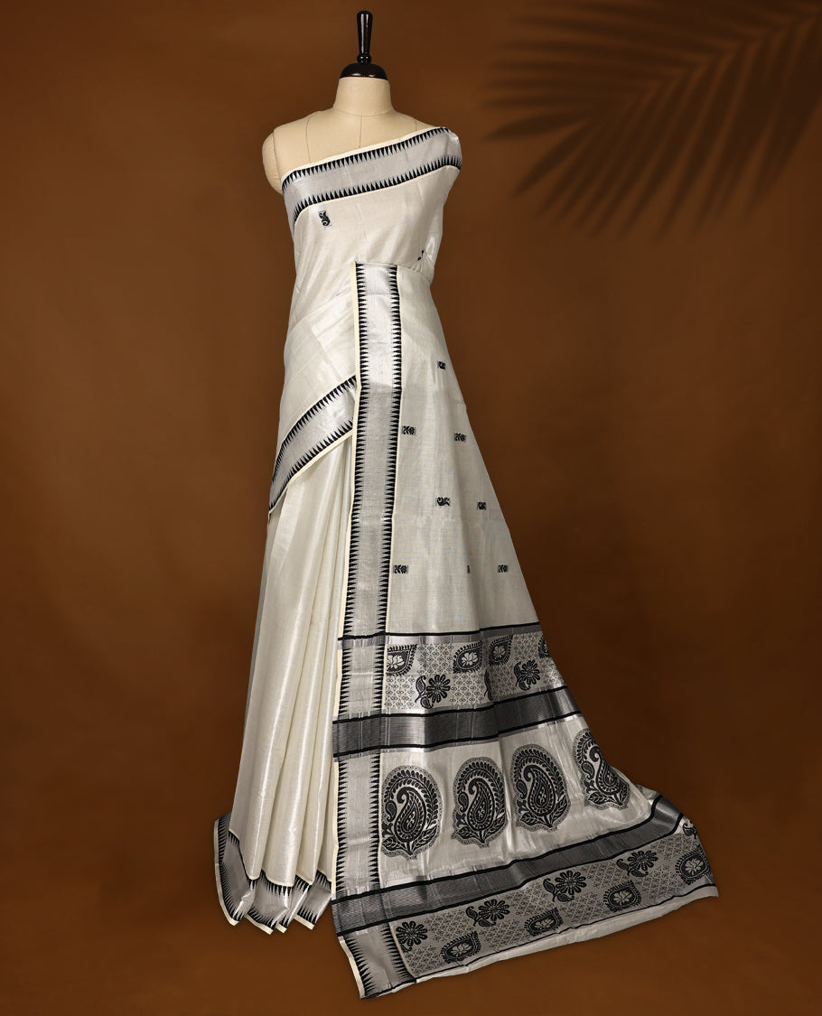 Elegant Tissue Kerala saree in off white colour featuring bold black paisley & floral motifs, woven on a sleek striped body with a striking black kasavu border and Paired with a matching blouse, perfect for festivities.