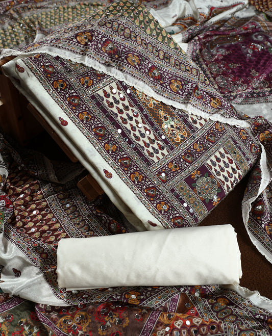 Off white colour churidhar material beautifully detailed with grape colour traditional paisley and floral prints, mirror work highlights, paired with a plain white bottom and a matching printed dupatta with lace border.