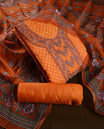 Vibrant orange churidhar material enhanced with delicate floral,stone and vine prints, paired with a plain matching bottom and a beautifully printed dupatta, perfect for festive elegance and traditional charm.