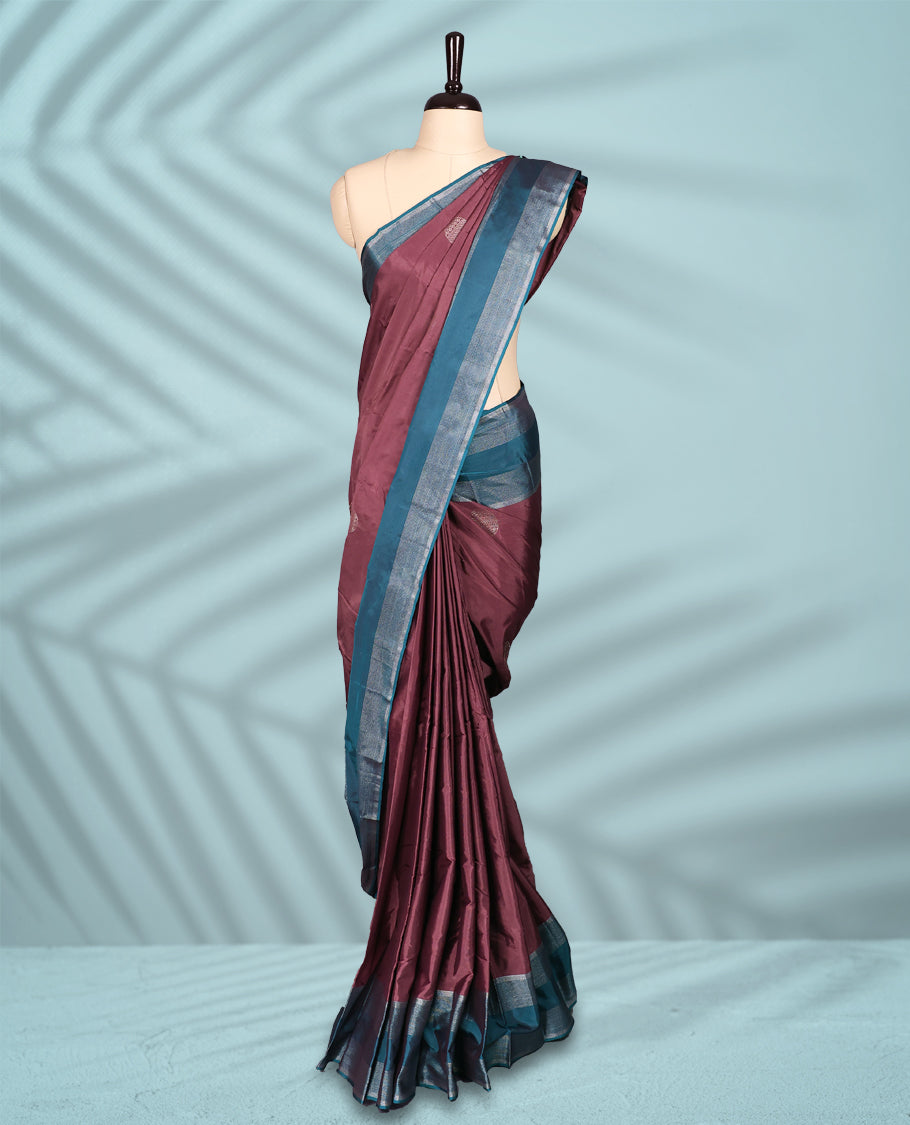 Onion coloured semi silk saree features silver zari motifs and is paired with a contrasting teal blue and silver zari border, with a matching blouse.