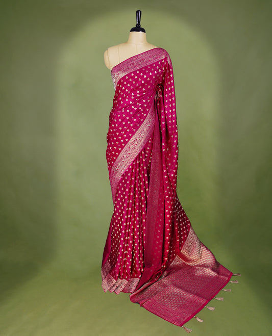 Rani Pink semi-Banaras satin crepe saree featuring traditional closely woven buttas on the body, complemented by an antique-style border and a matching self-coloured blouse.