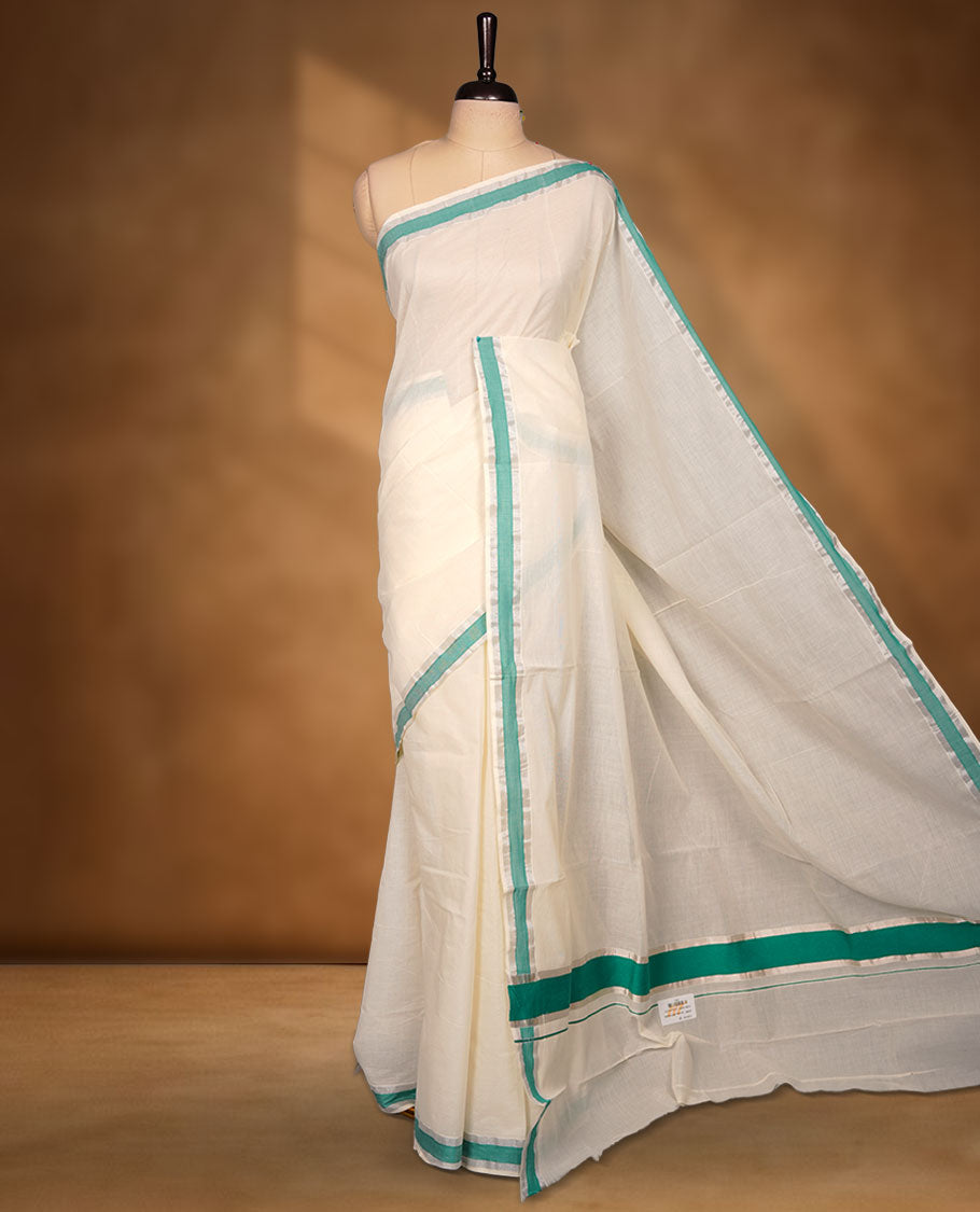 Off-white colour cotton Kerala saree featuring a crisp white body with a refreshing green kasavu border, detailed with subtle silver accents along the edges, and paired with a matching blouse.