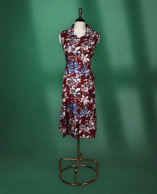 Maroon colour sleeveless dress featuring a collared neckline and button down front, adorned with bold blue and white floral prints a stylish and breathable choice for everyday elegance.