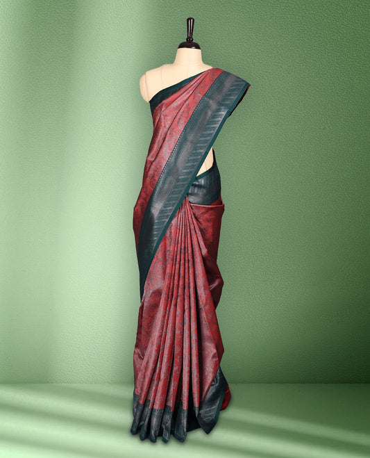 Brick Red colour semi silk saree featuring neem zari floral kodi motifs all over the body, complemented by a rich green woven border with geometric detailing, with matching blouse.