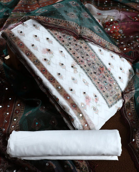 White colour churidhar material with mirror work and pastel floral prints, highlighted by earthy geometric borders & Comes with a plain white bottom and a dark green net dupatta adorned with shimmering mirror embellishments.