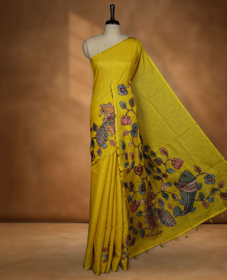 Mustard yellow semi linen saree featuring hand painted floral and bird motifs along the pallu and lower body, finished with a subtle border and paired with a matching printed blouse.
