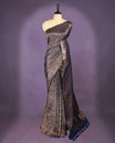 Navy blue colour semi Banaras Katan silk saree featuring intricate Antique Bronze zari floral and vine patterns woven throughout the body, enhanced with a rich traditional border and detailed pallu, paired with a matching blouse piece.