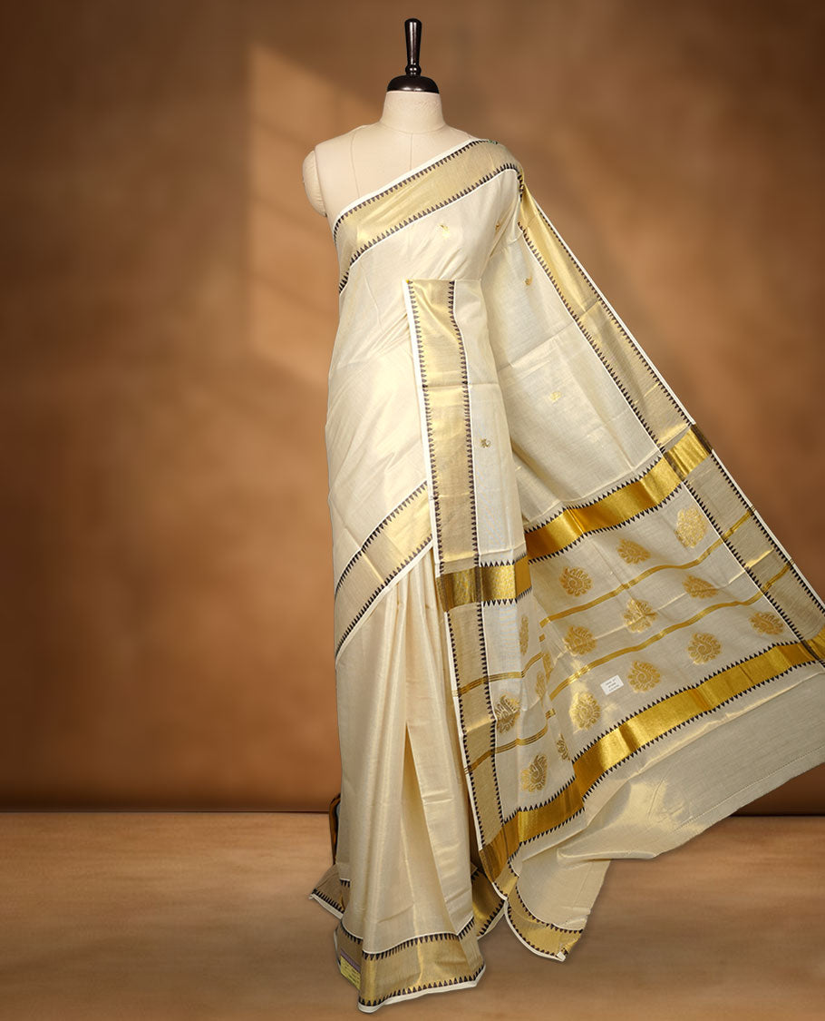 Light gold colour tissue Kerala saree featuring delicate gold zari buttas across the body, finished with a classic kasavu border highlighted by black triangle detailing, paired with a matching blouse.